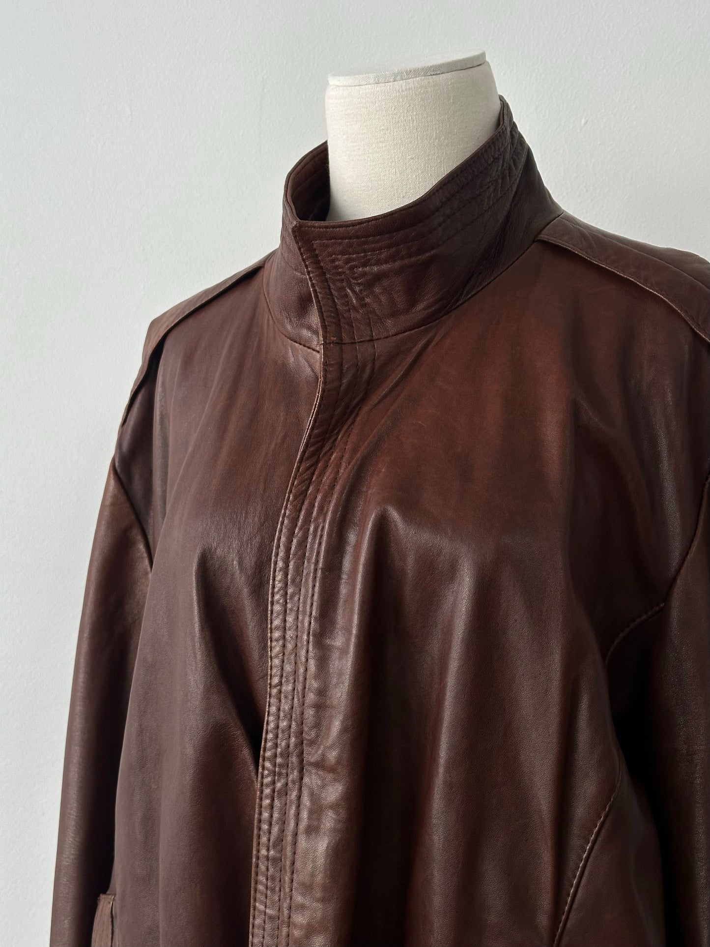 Vintage British 1980s high neck leather bomber jacket, stylish and classic, shown in a natural front view.