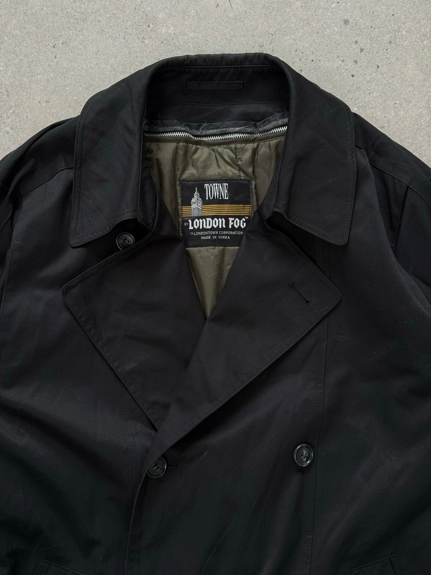London Fog Towne 1990s double-breasted belted trench coat hanging with a classic design and neutral color.