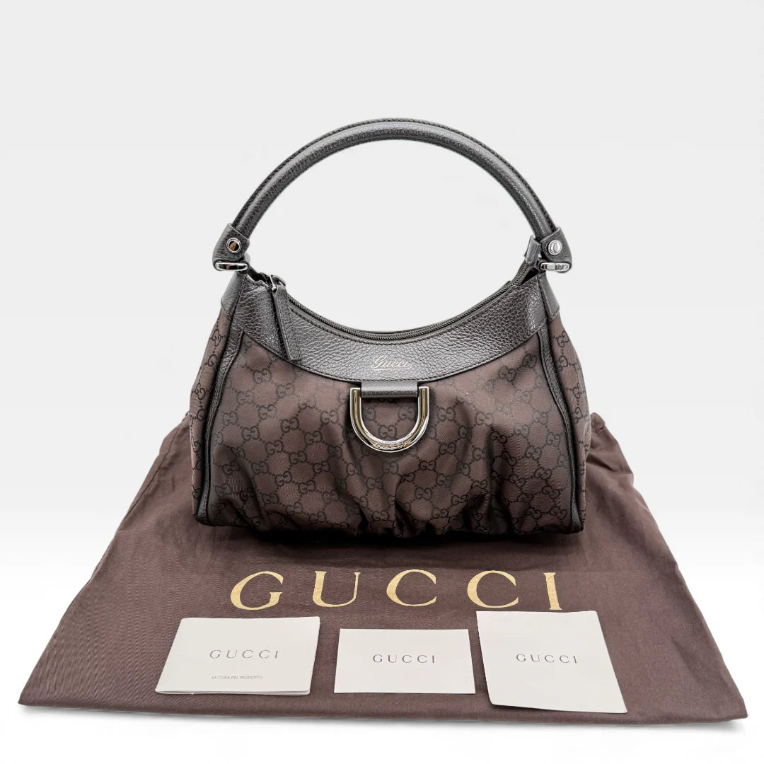 https://cdn.shopify.com/s/files/1/0564/9376/8855/files/Gucci_Handtasche_D-Ring_aus_Nylon_monogram_dunkelbraun_vintage_GG_handbag_5302.webp?v=1765384494
