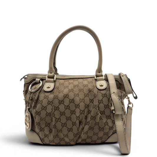 https://cdn.shopify.com/s/files/1/0564/9376/8855/files/Gucci_Handtasche_Sukey_mit_Umhangegurt_monogram_beige_vintage_GG7928.webp?v=1779966403