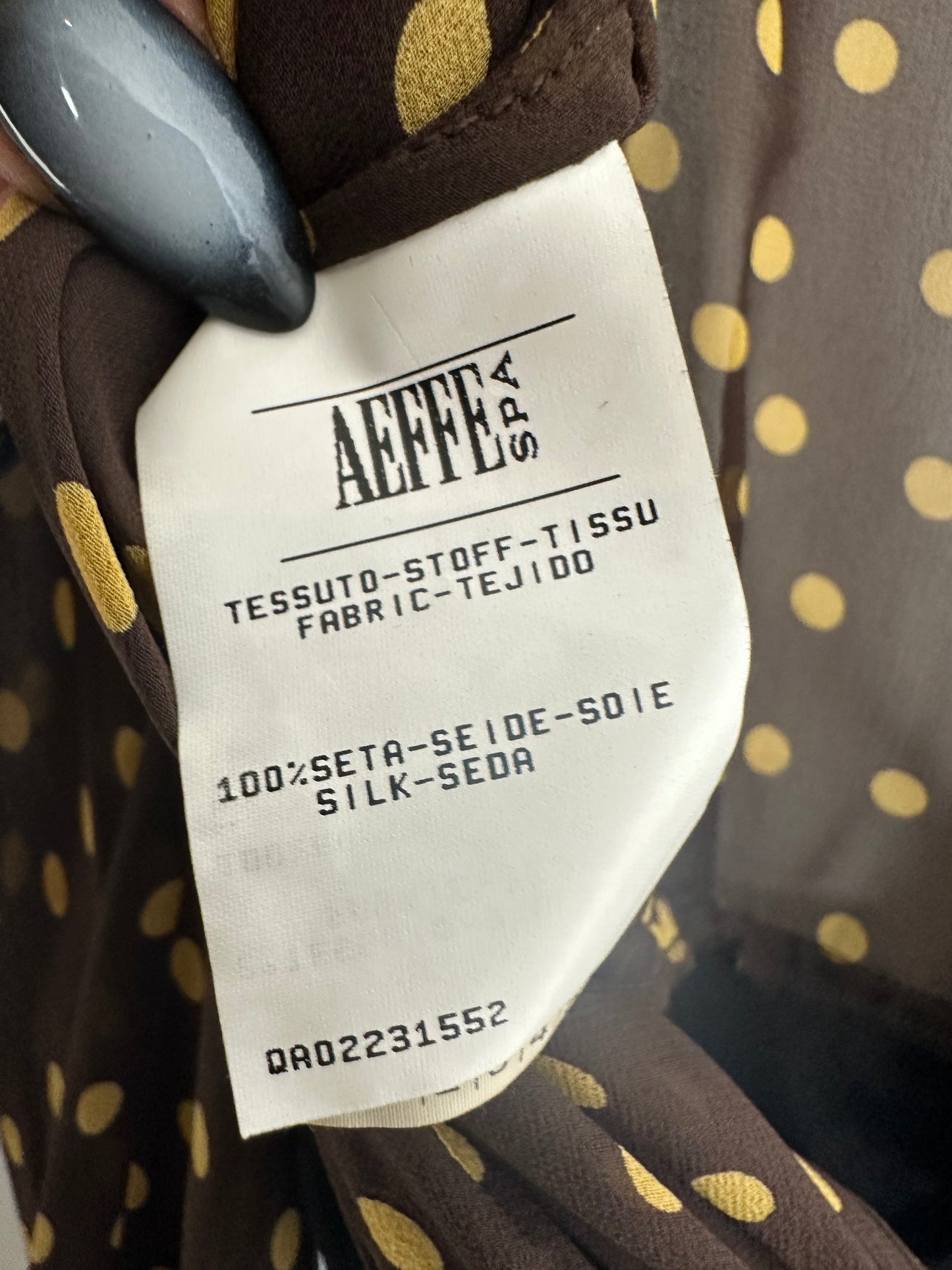 Close-up of a fabric tag on a brown garment with gold polka dots, featuring the brand 'AEFFE'.