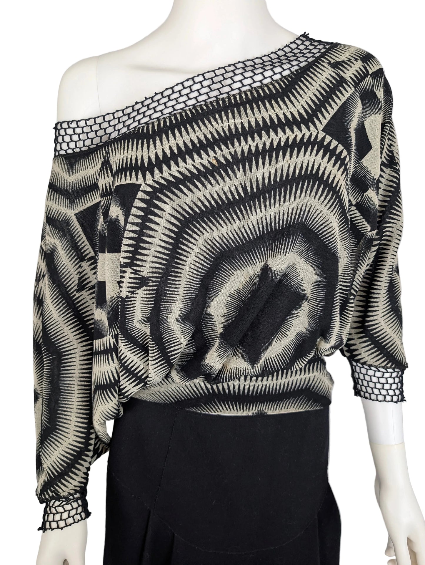 Mannequin wearing a black and white patterned top with long sleeves on a plain background