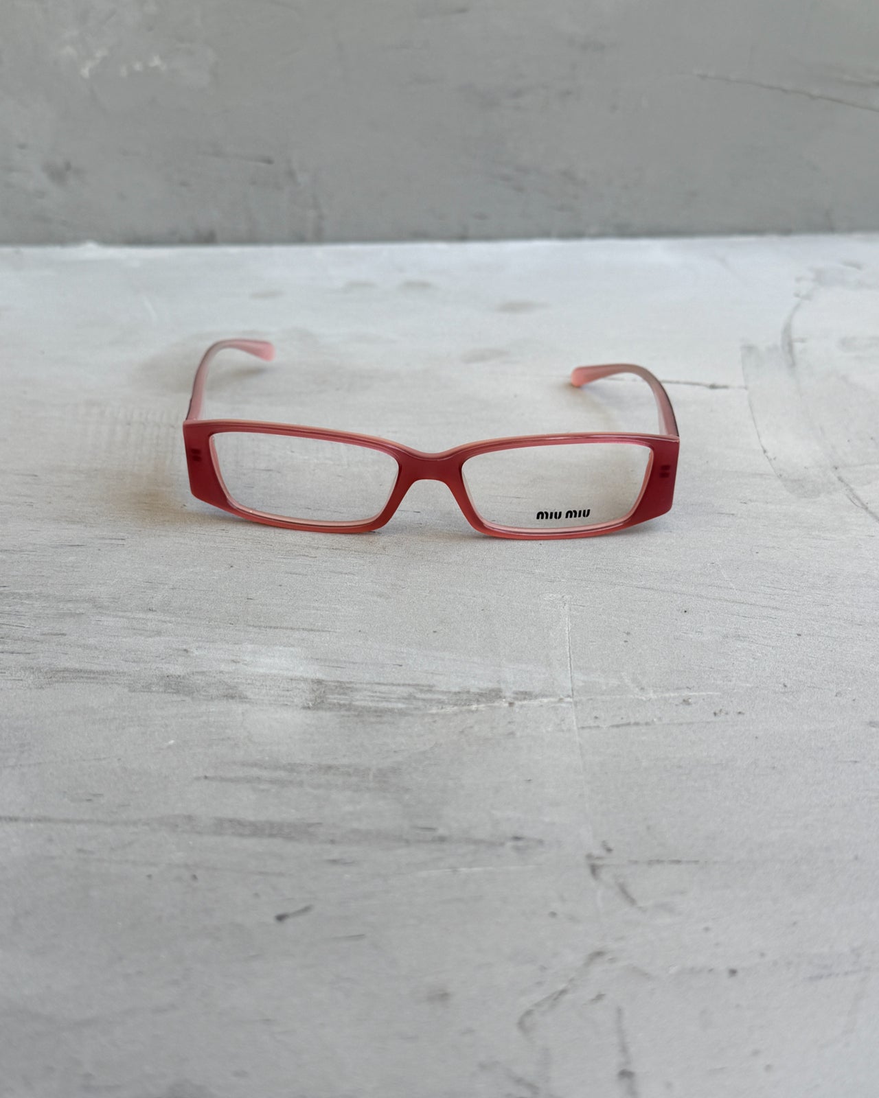 Miu Miu Pink Clear Lens Glasses-on a concrete background