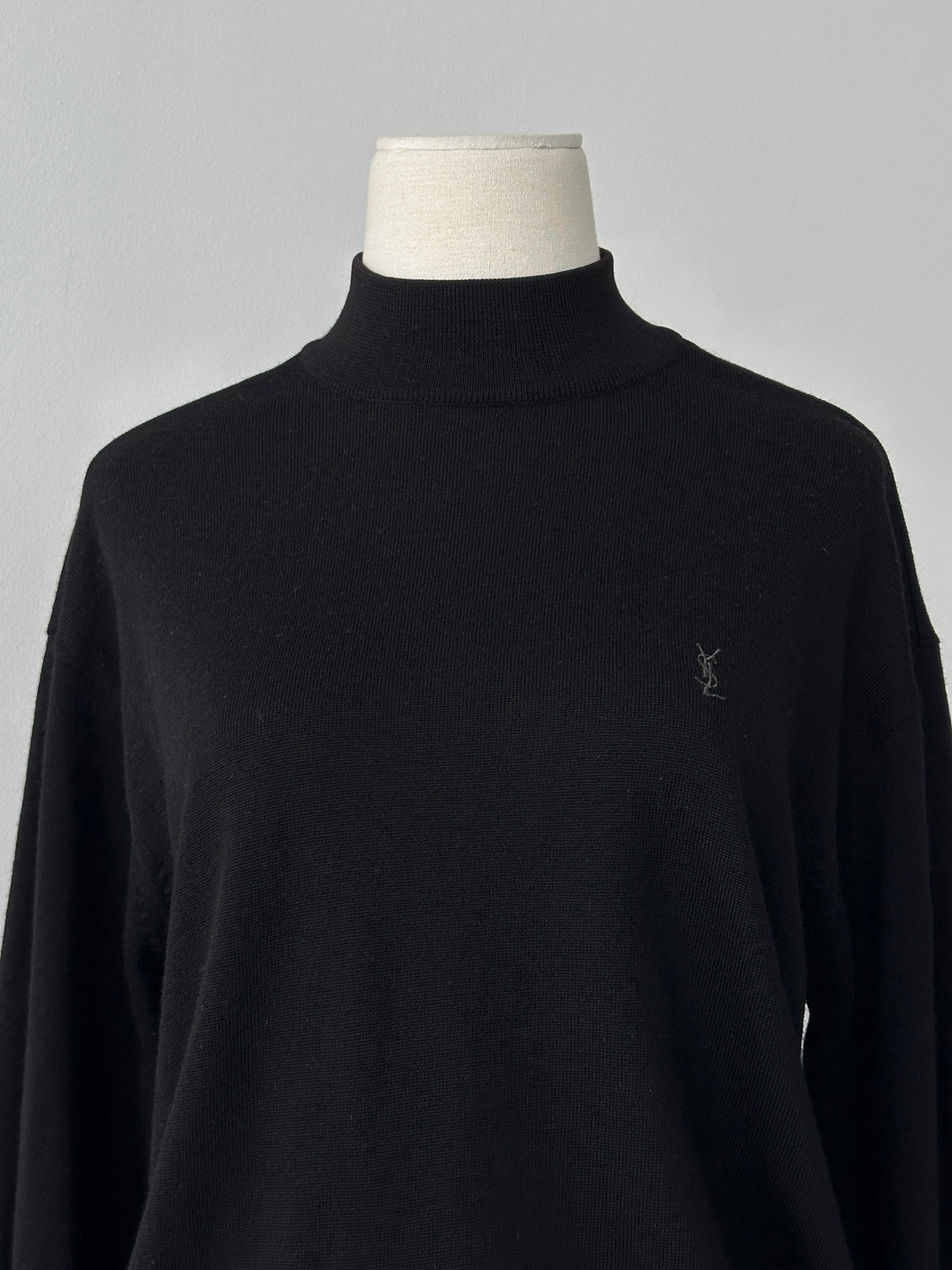 Yves Saint Laurent 1990s wool high neck jumper in black, featuring a classic fit and ribbed collar, displayed on a hanger.