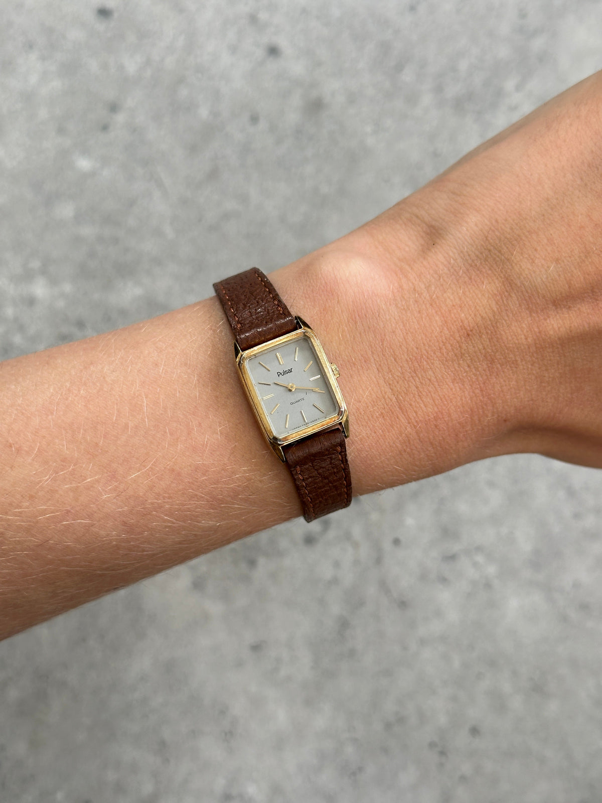 Vintage Pulsar 1980s gold-tone leather watch with round face and classic design, featuring leather strap and vintage style.