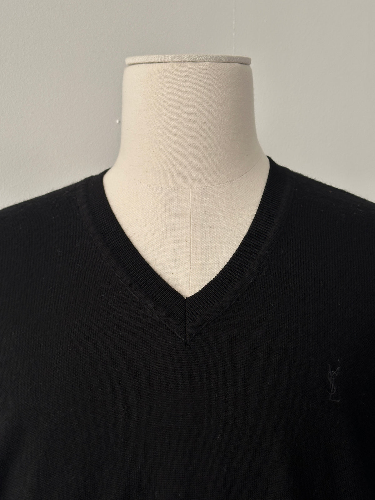 Yves Saint Laurent 1990s pure wool V-neck jumper in size M, displayed on a hanger, showcasing its classic design and soft texture.