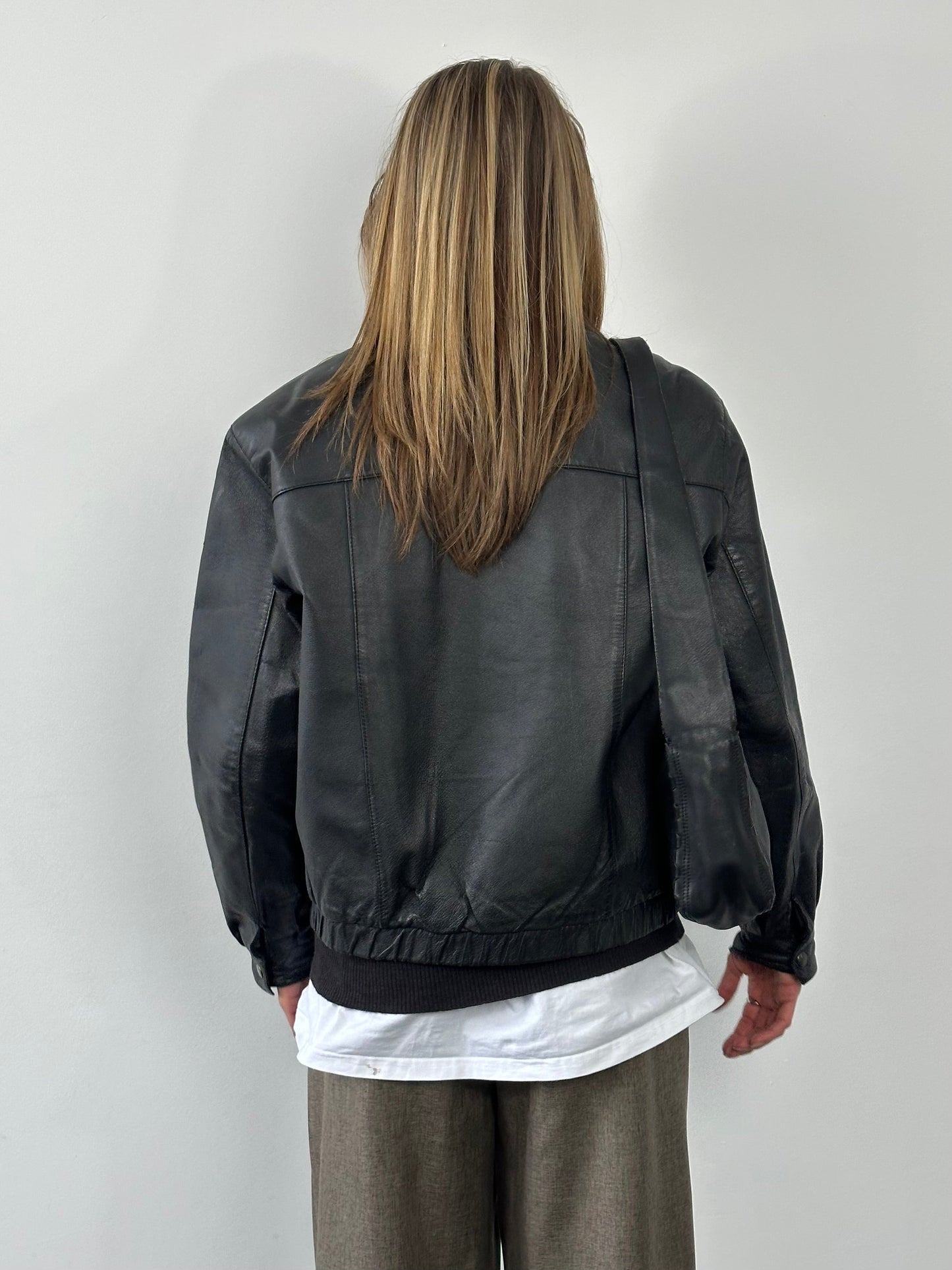 Vintage 1990s leather bomber jacket in size M, featuring classic design with a worn-in leather finish and ribbed collar.