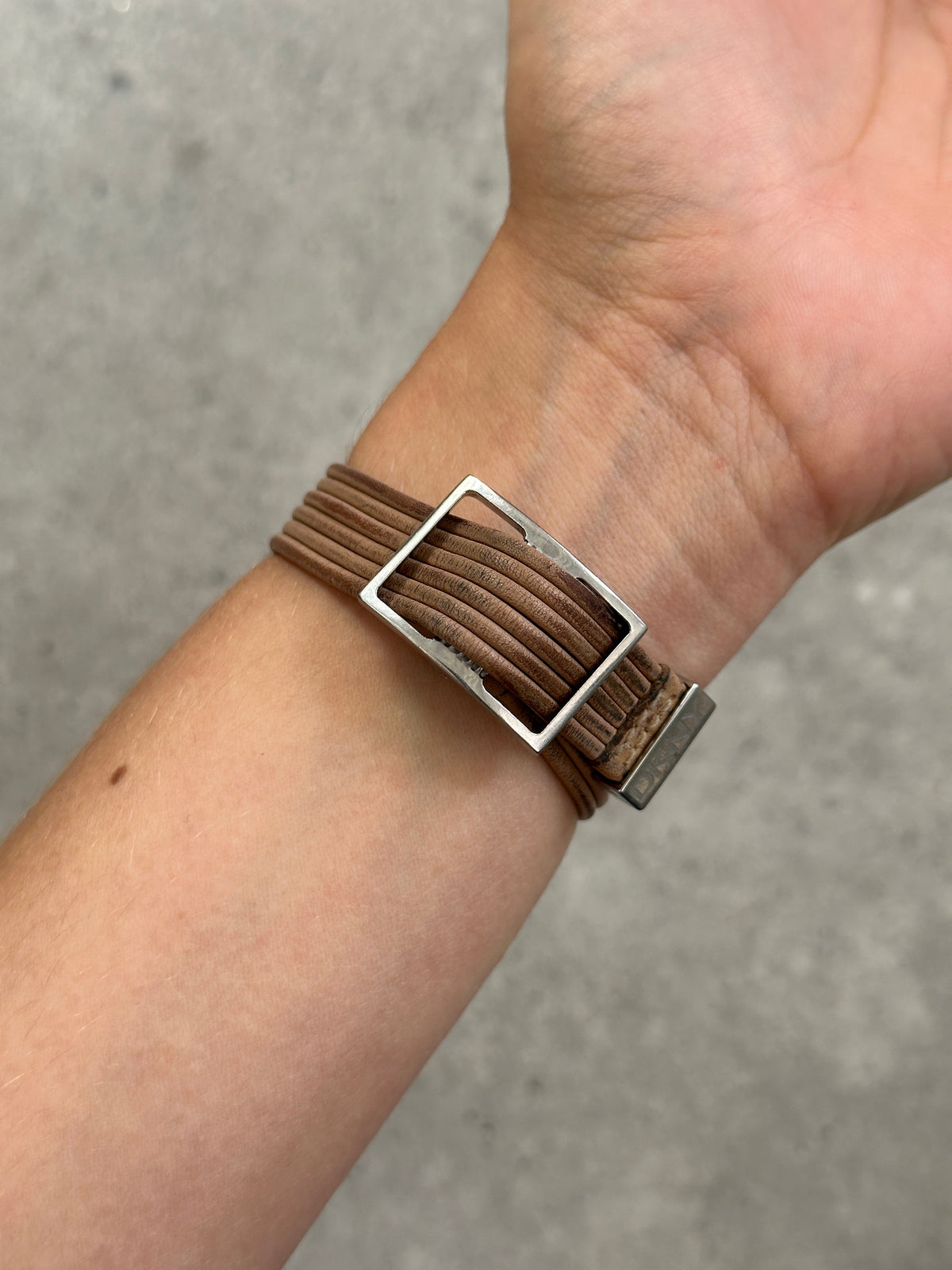 Donna Karran DKNY 2000s leather rectangular quartz watch with gold-tone case and black leather strap, close-up of watch face.