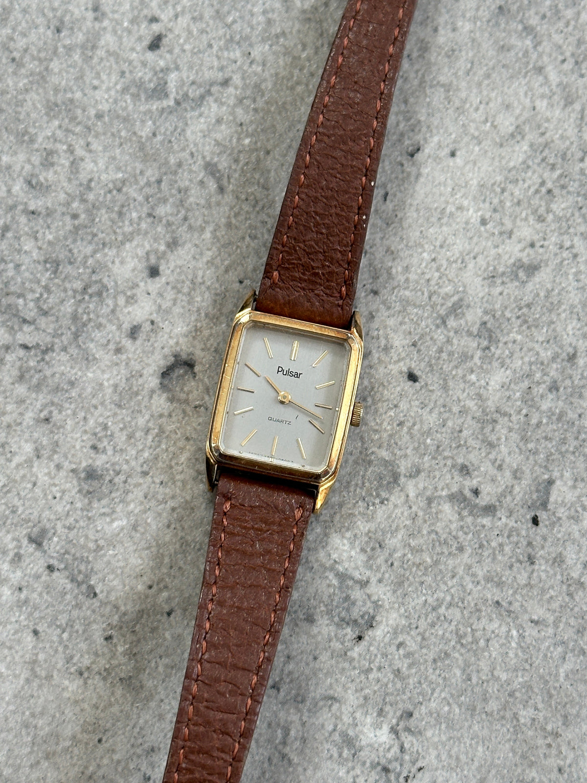Vintage Pulsar 1980s gold tone leather watch with round dial, classic design, and leather strap.