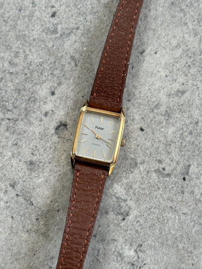 Vintage Pulsar 1980s gold tone leather watch with round dial, classic design, and leather strap.