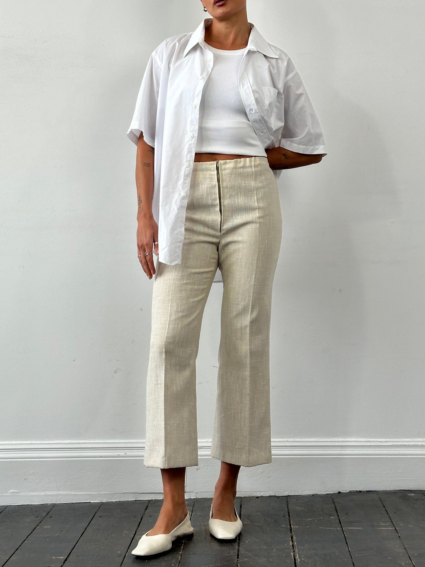 Vintage 1990s linen high-waist cropped trousers in beige, showing waistline and relaxed fit, with textured fabric details.
