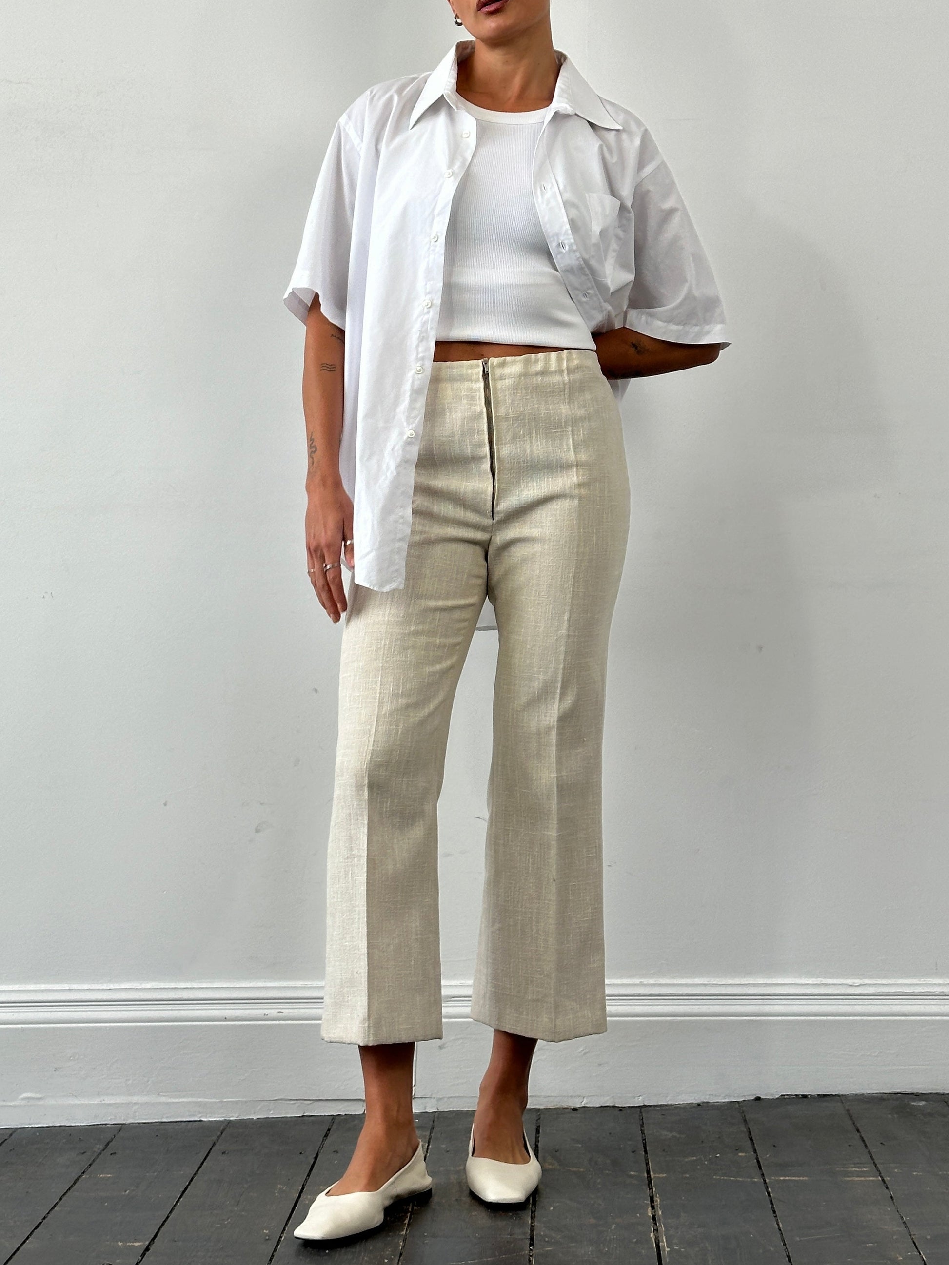 Vintage 1990s linen high-waist cropped trousers in beige, showing waistline and relaxed fit, with textured fabric details.