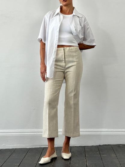 Vintage 1990s linen high-waist cropped trousers in beige, showing waistline and relaxed fit, with textured fabric details.
