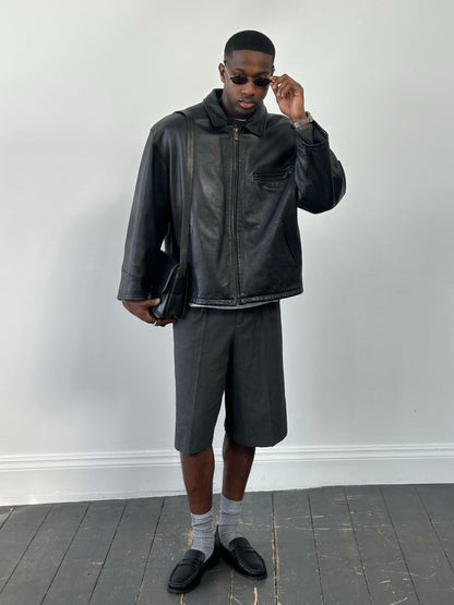 Vintage 1990s heavyweight leather jacket, minimal design, oversized fit, black leather, vintage brand, detailed close-up view.