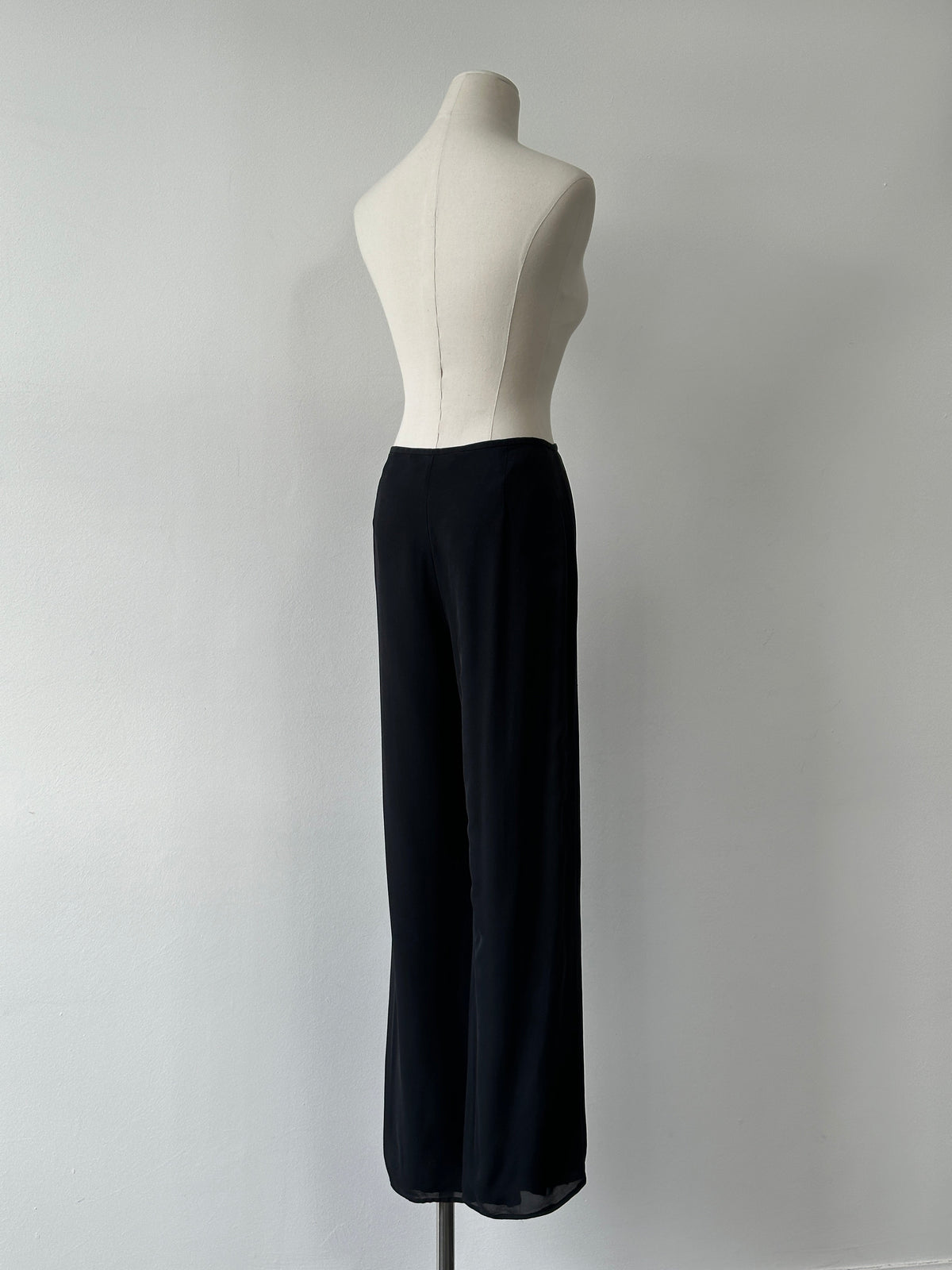Vintage 1990s pure silk wide leg trousers in size W30, showcasing smooth fabric and relaxed fit on a hanger.