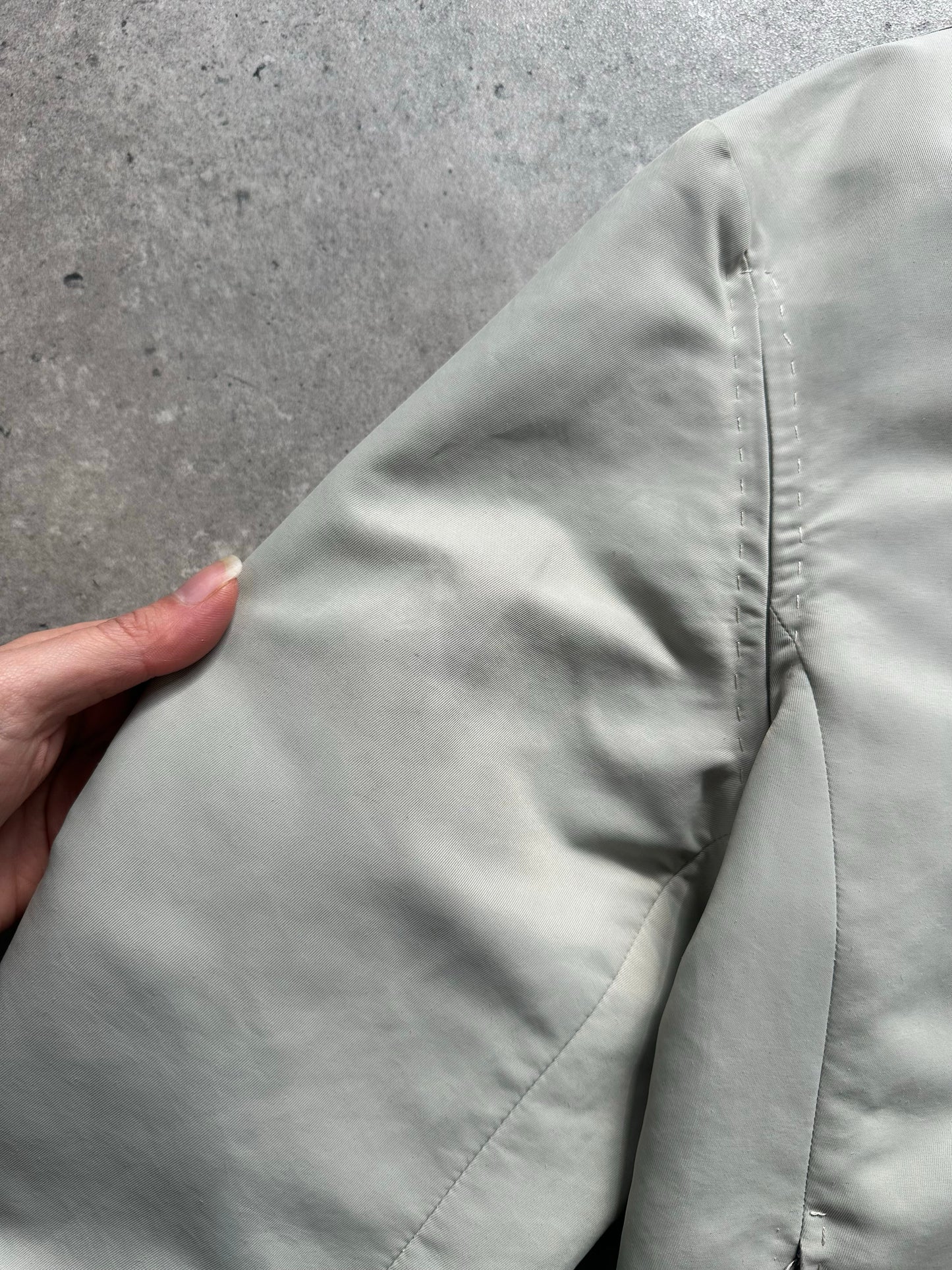 Gianfranco Ferre 1990s showerproof minimal jacket in size L, featuring sleek design and lightweight fabric, displayed on a hanger.