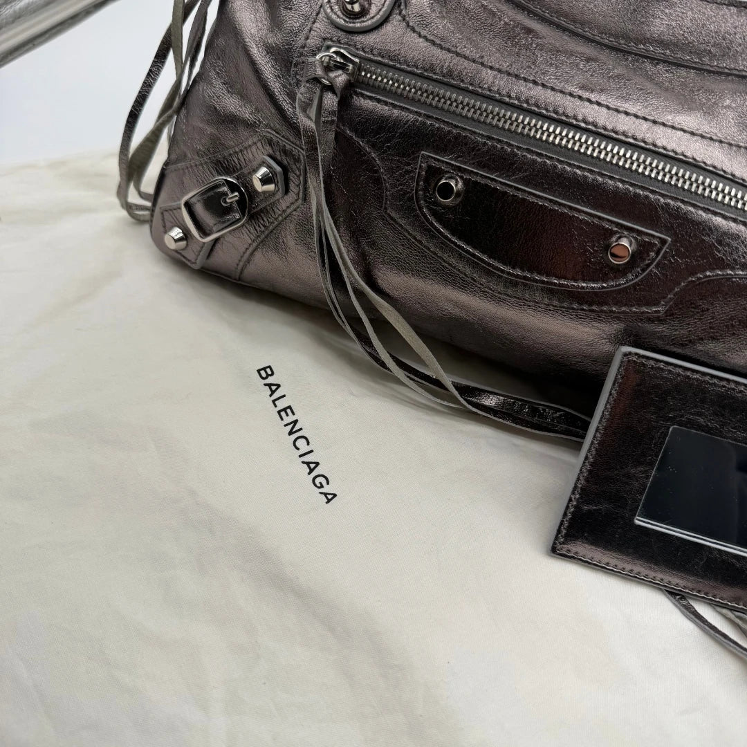 https://cdn.shopify.com/s/files/1/0564/9376/8855/files/Balenciaga_Handtasche_The_First_City_Bag_aus_Leder_silber___chrome_vintage6600.webp?v=1778675915