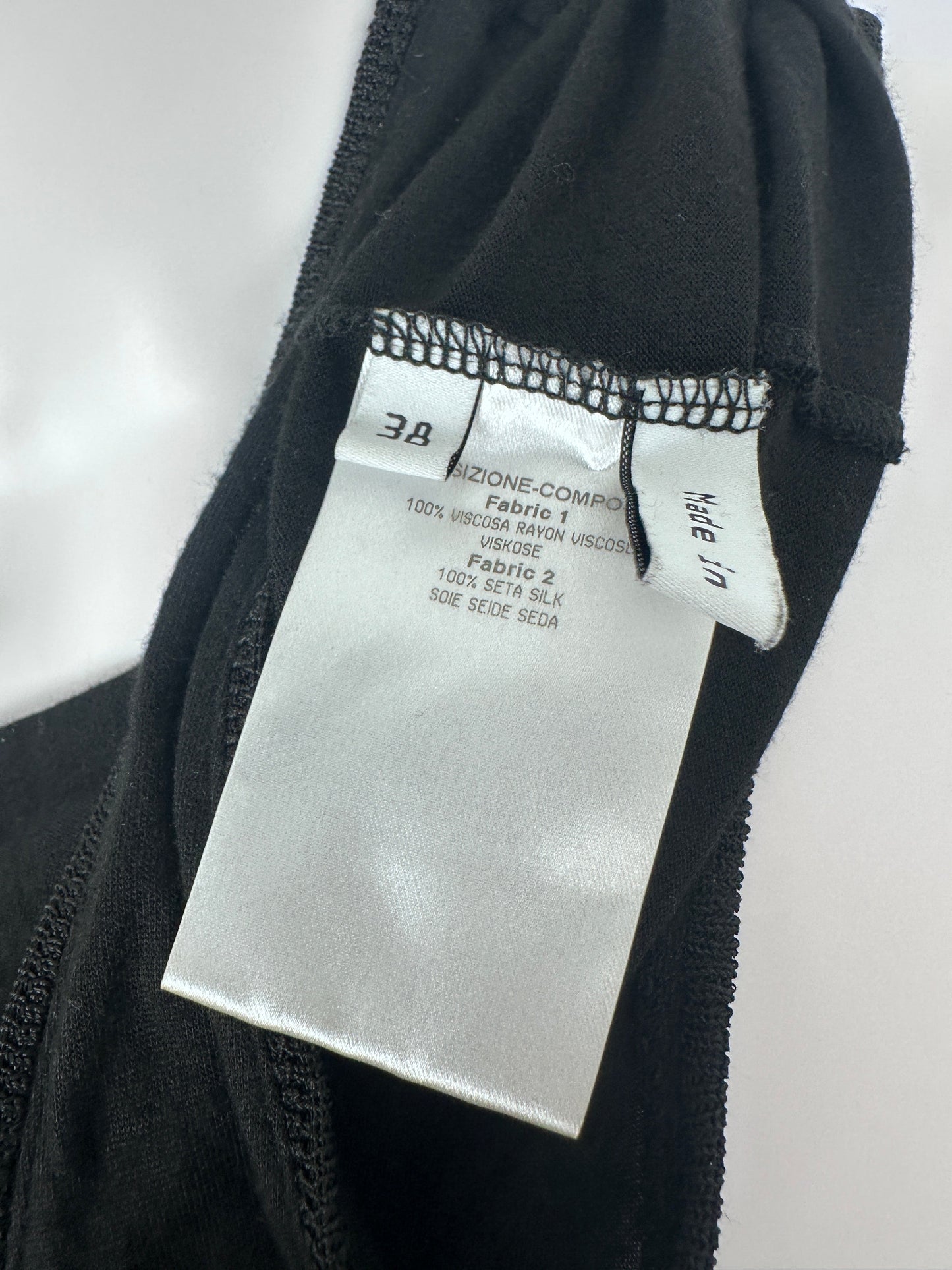 Close-up of a black garment with a silver label on a white background