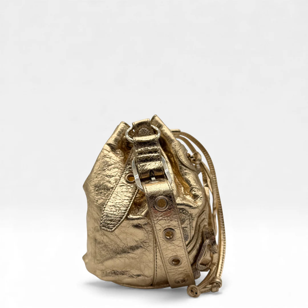 https://cdn.shopify.com/s/files/1/0564/9376/8855/files/Balenciaga_Umhangetasche_Le_Cagole_bucket_XS_aus_Leder_gold_crossbody_bag_5322.webp?v=1766108471