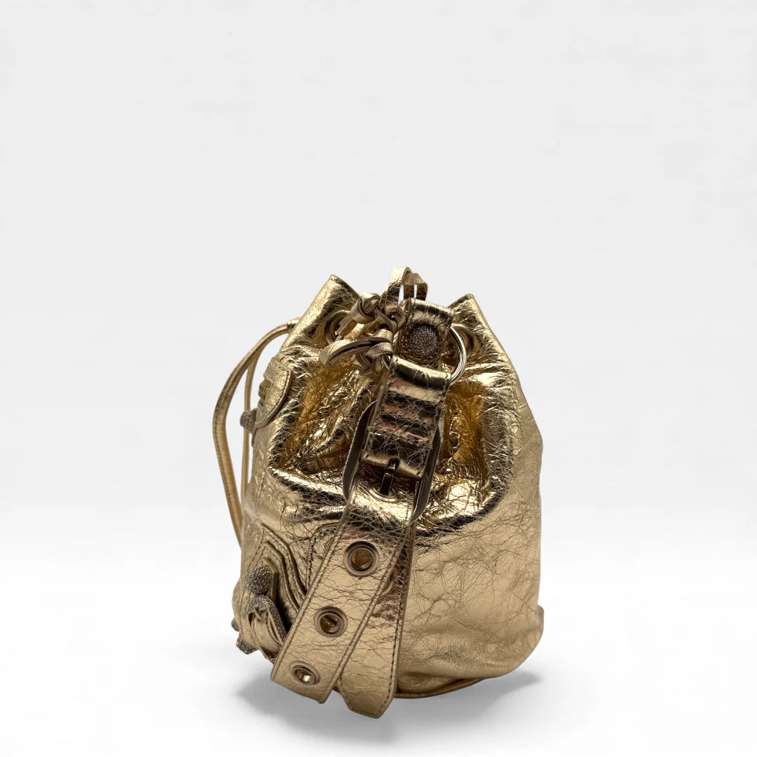 https://cdn.shopify.com/s/files/1/0564/9376/8855/files/Balenciaga_Umhangetasche_Le_Cagole_bucket_XS_aus_Leder_gold_crossbody_bag_5323.webp?v=1766108471