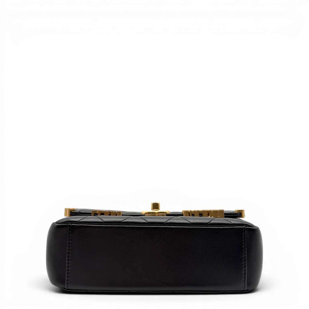 https://cdn.shopify.com/s/files/1/0564/9376/8855/files/Chanel_Handtasche_Cruise_23C_Mini_Flap_bag_mit_Emaille-_und_Strassdetails_aus_Lammleder_schwarz_vintage_CC7185_89228f11-a35a-416d-858b-db2a0901ec09.webp?v=1779959981