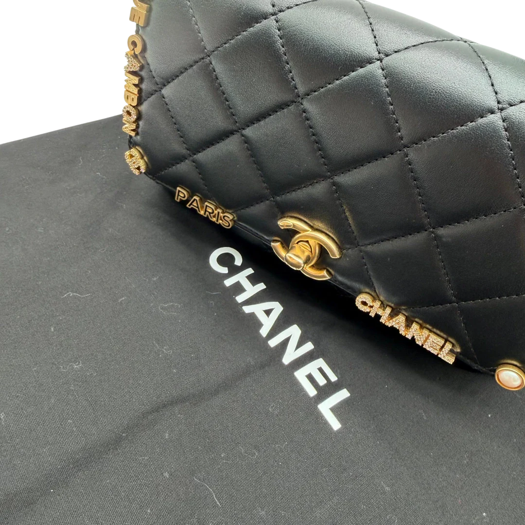 https://cdn.shopify.com/s/files/1/0564/9376/8855/files/Chanel_Handtasche_Cruise_23C_Mini_Flap_bag_mit_Emaille-_und_Strassdetails_aus_Lammleder_schwarz_vintage_CC7202_4f1b9c0c-6db0-4188-a262-0ea51bf49398.webp?v=1779959982