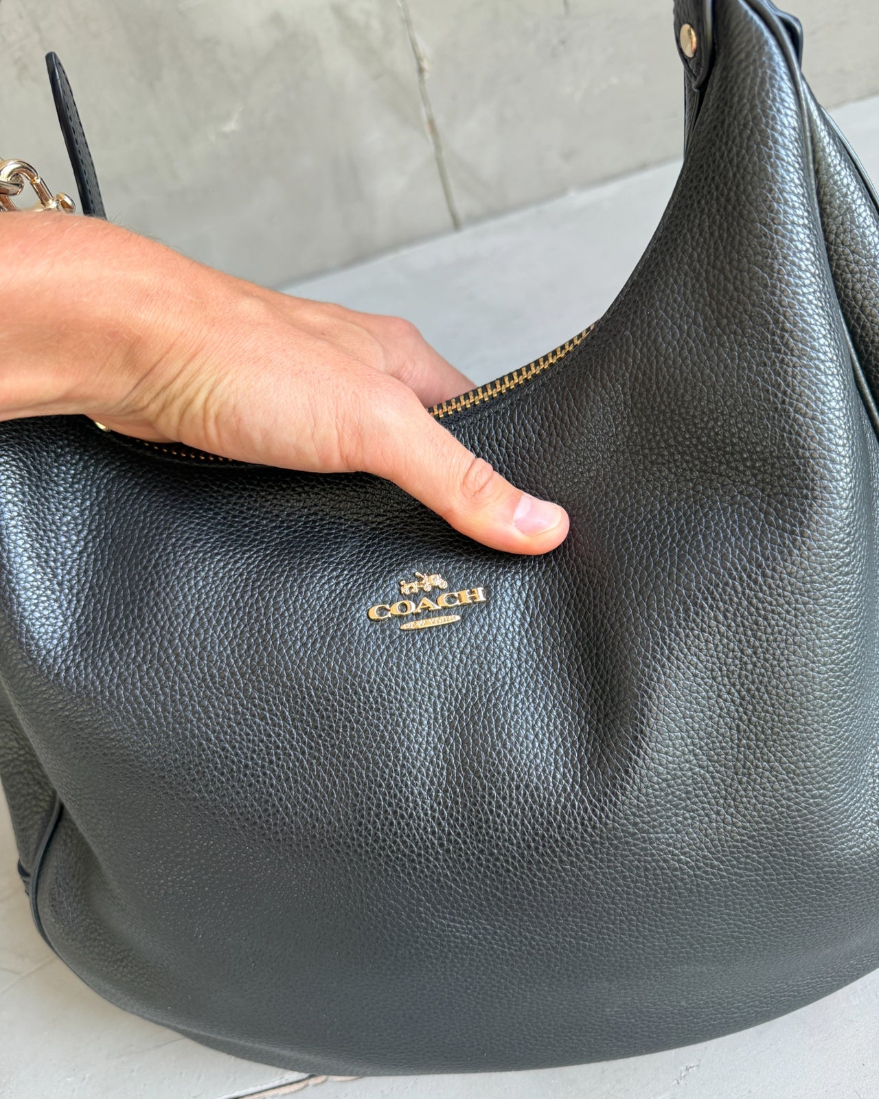 Coach Black Leather Shoulder Bag with Crossbody Strap-on a concrete background