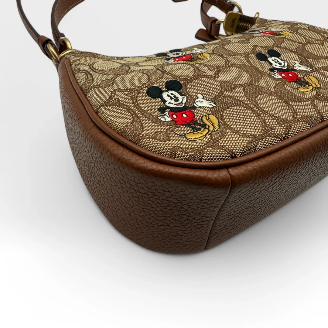 https://cdn.shopify.com/s/files/1/0564/9376/8855/files/Coach_x_Disney_Handtasche_Pochette_mit_Umhaengegurt_monogram_braun_vintage_luxury_handbag_2612.webp?v=1743622420