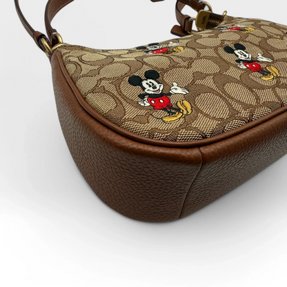 https://cdn.shopify.com/s/files/1/0564/9376/8855/files/Coach_x_Disney_Handtasche_Pochette_mit_Umhaengegurt_monogram_braun_vintage_luxury_handbag_2612.webp?v=1743622420