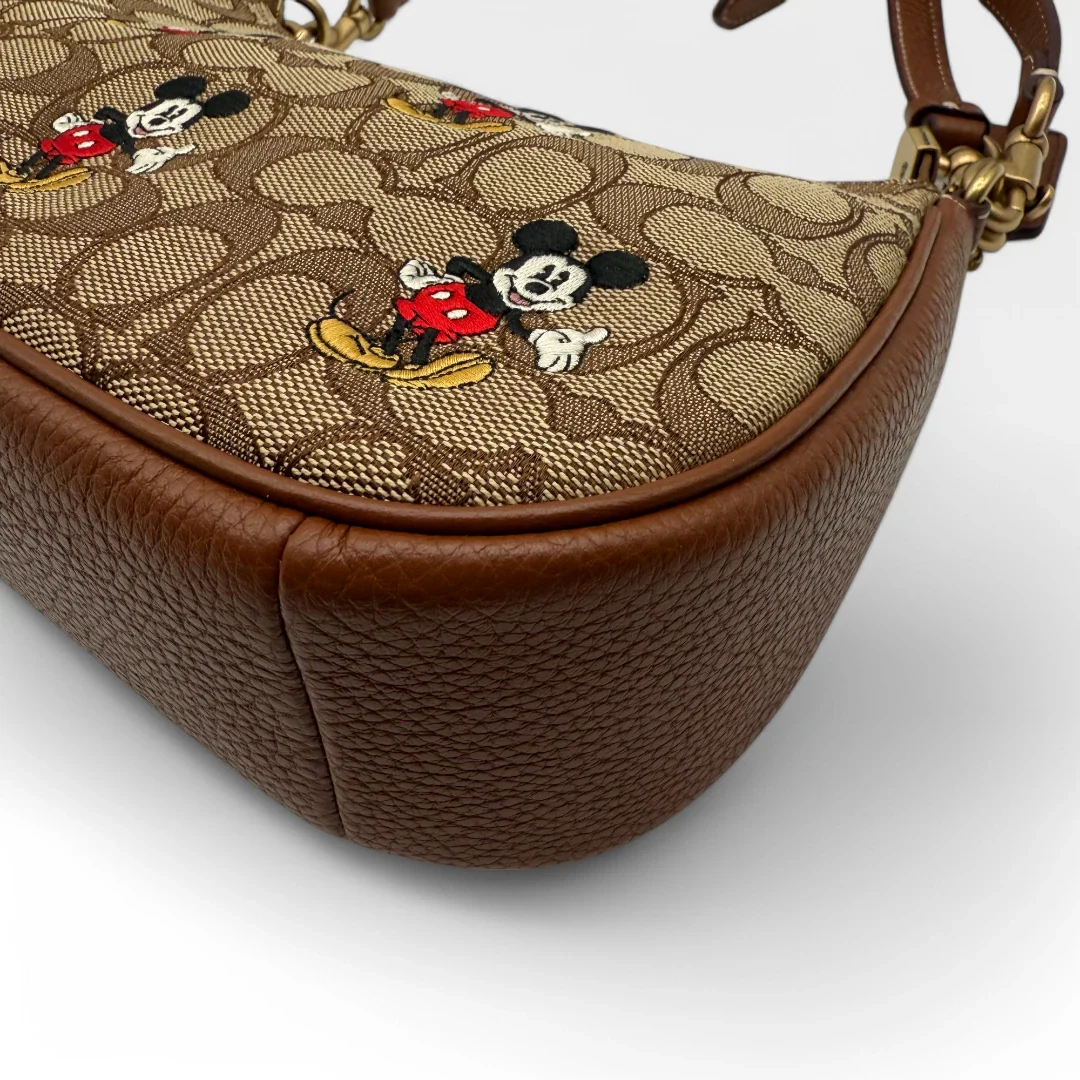 https://cdn.shopify.com/s/files/1/0564/9376/8855/files/Coach_x_Disney_Handtasche_Pochette_mit_Umhaengegurt_monogram_braun_vintage_luxury_handbag_2613.webp?v=1743622420