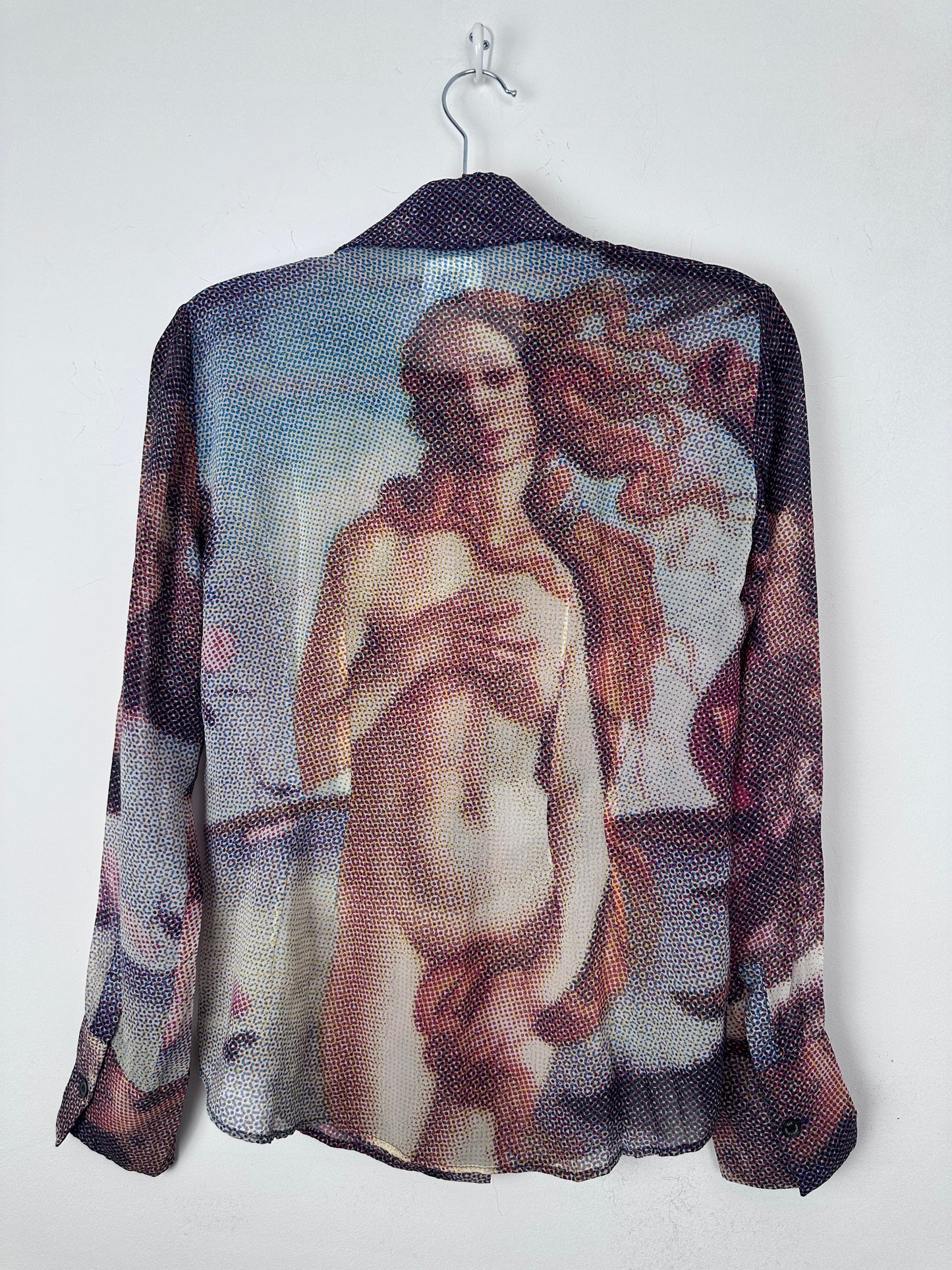 A sheer mesh shirt featuring a printed classical painting of a nude female figure, draped over a black hanger against a plain white background.