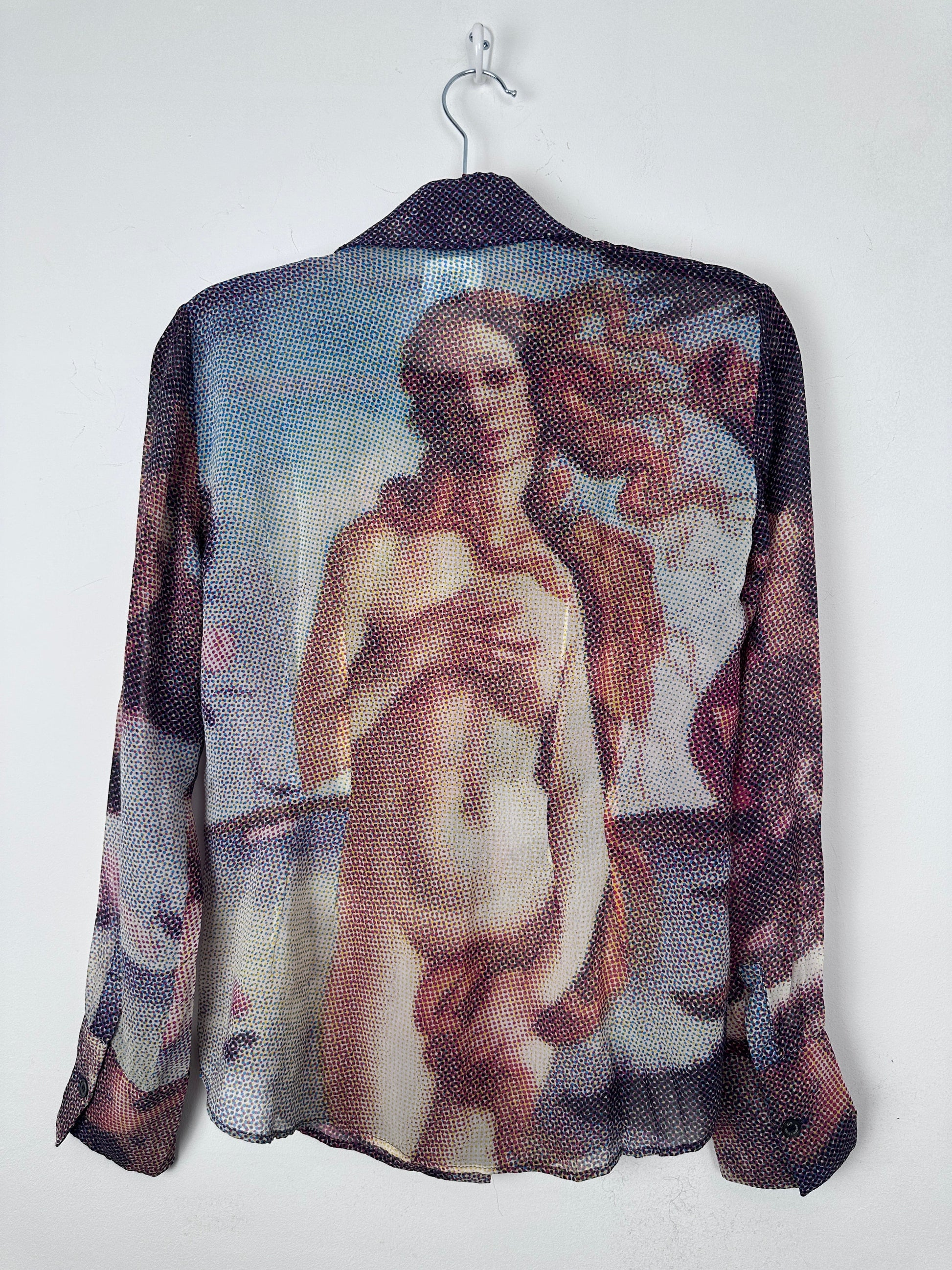 A sheer mesh shirt featuring a printed classical painting of a nude female figure, draped over a black hanger against a plain white background.