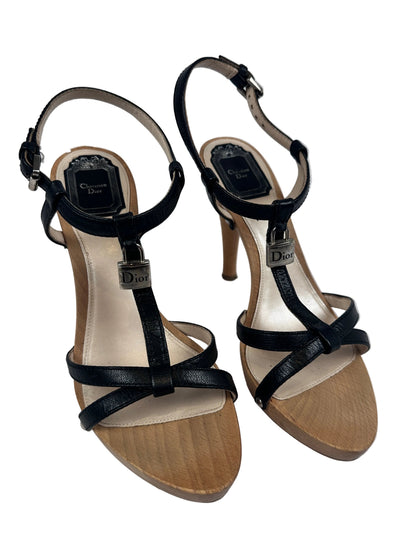 A pair of women's high-heeled sandals with black straps, a beige insole, and a light brown wood-look platform sole, shown from a top-down view on a white background.