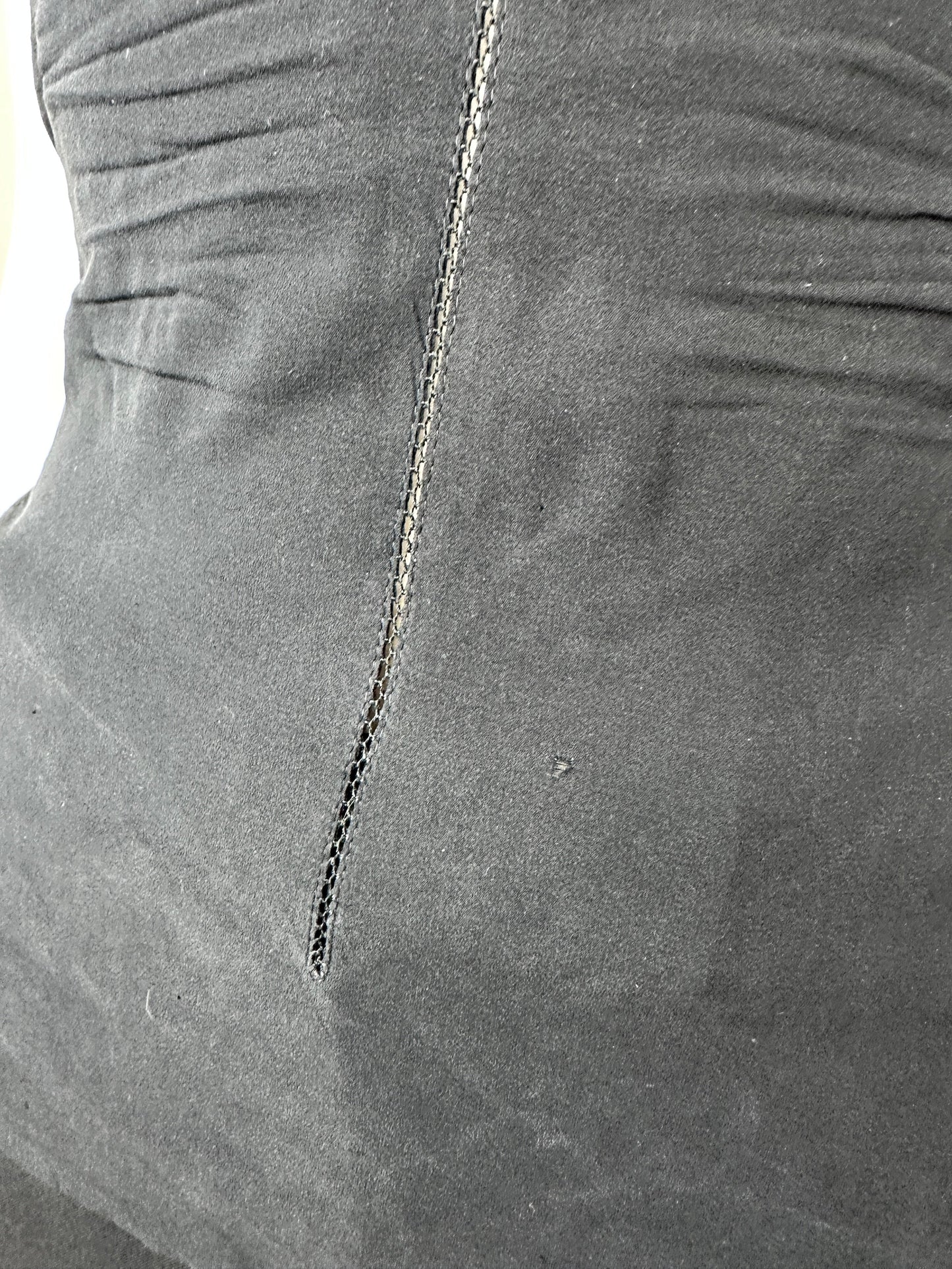 Close-up of a dark gray fabric surface with a visible seam and stitched detail.