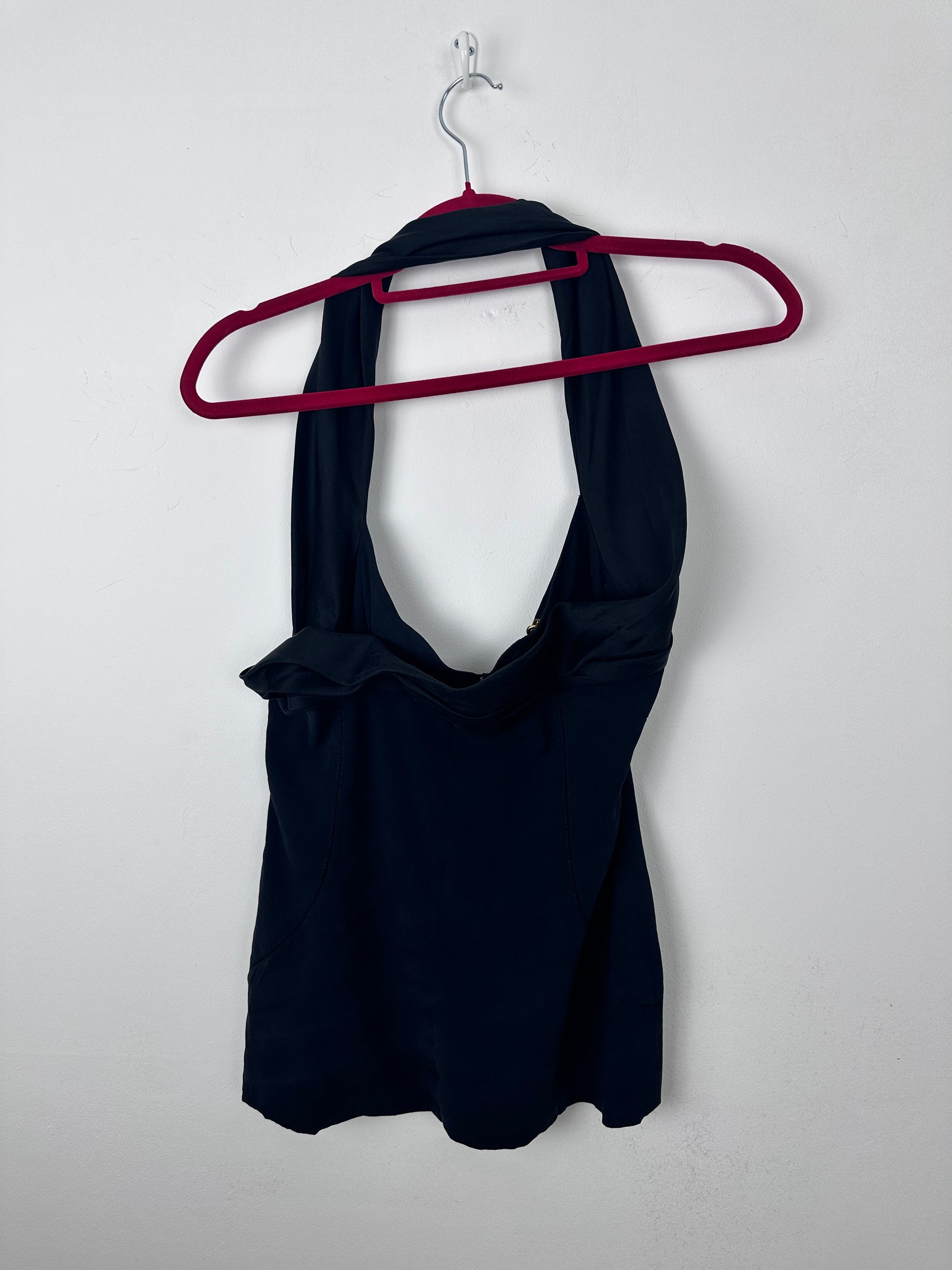 A dark navy sleeveless top or dress laid flat on a light gray background, draped over a dark red hanger.