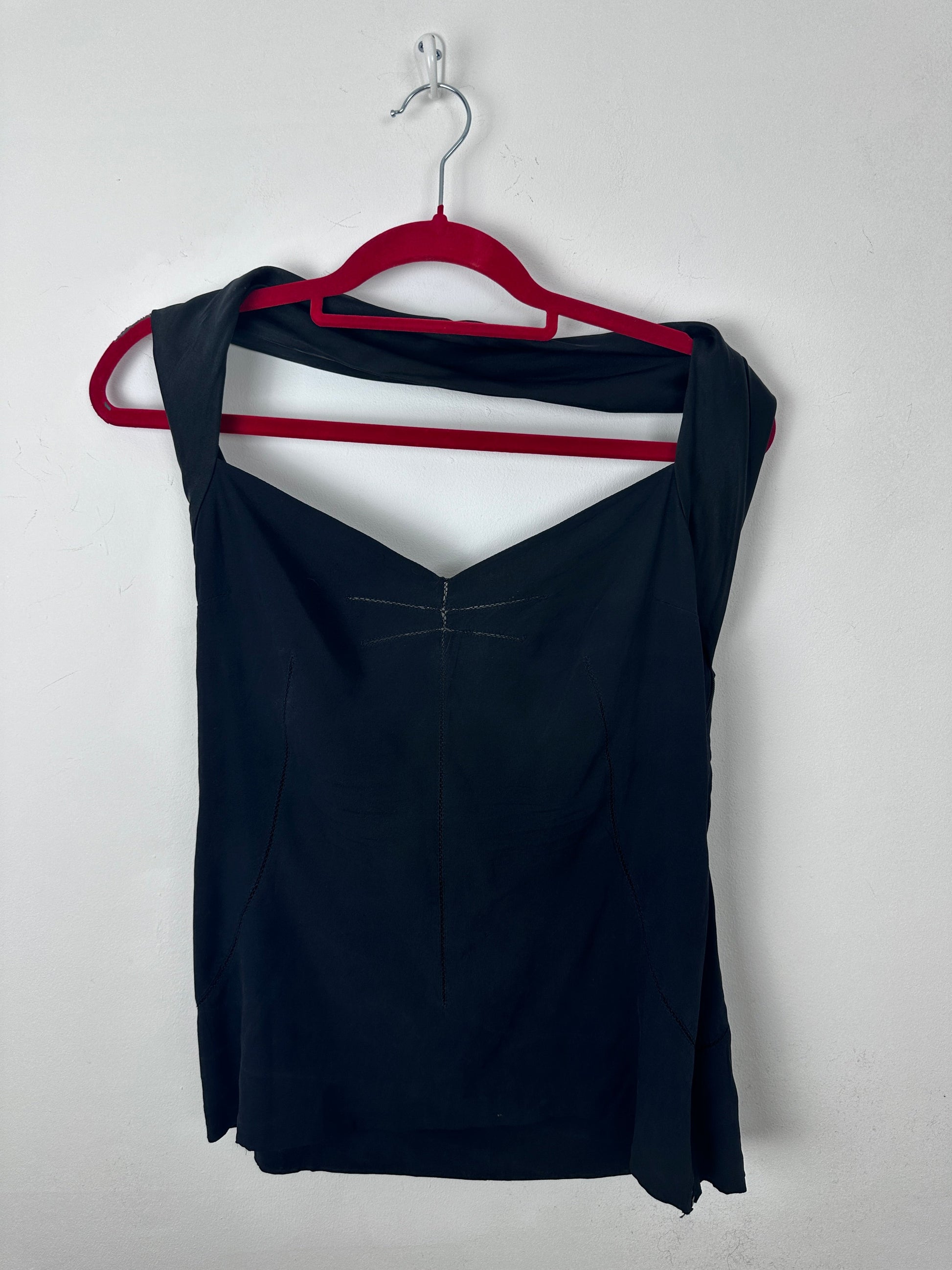 A black sleeveless top or dress with a red underwire-style trim and a white triangular cutout detail, laid flat on a white background with a red hanger visible on the left.
