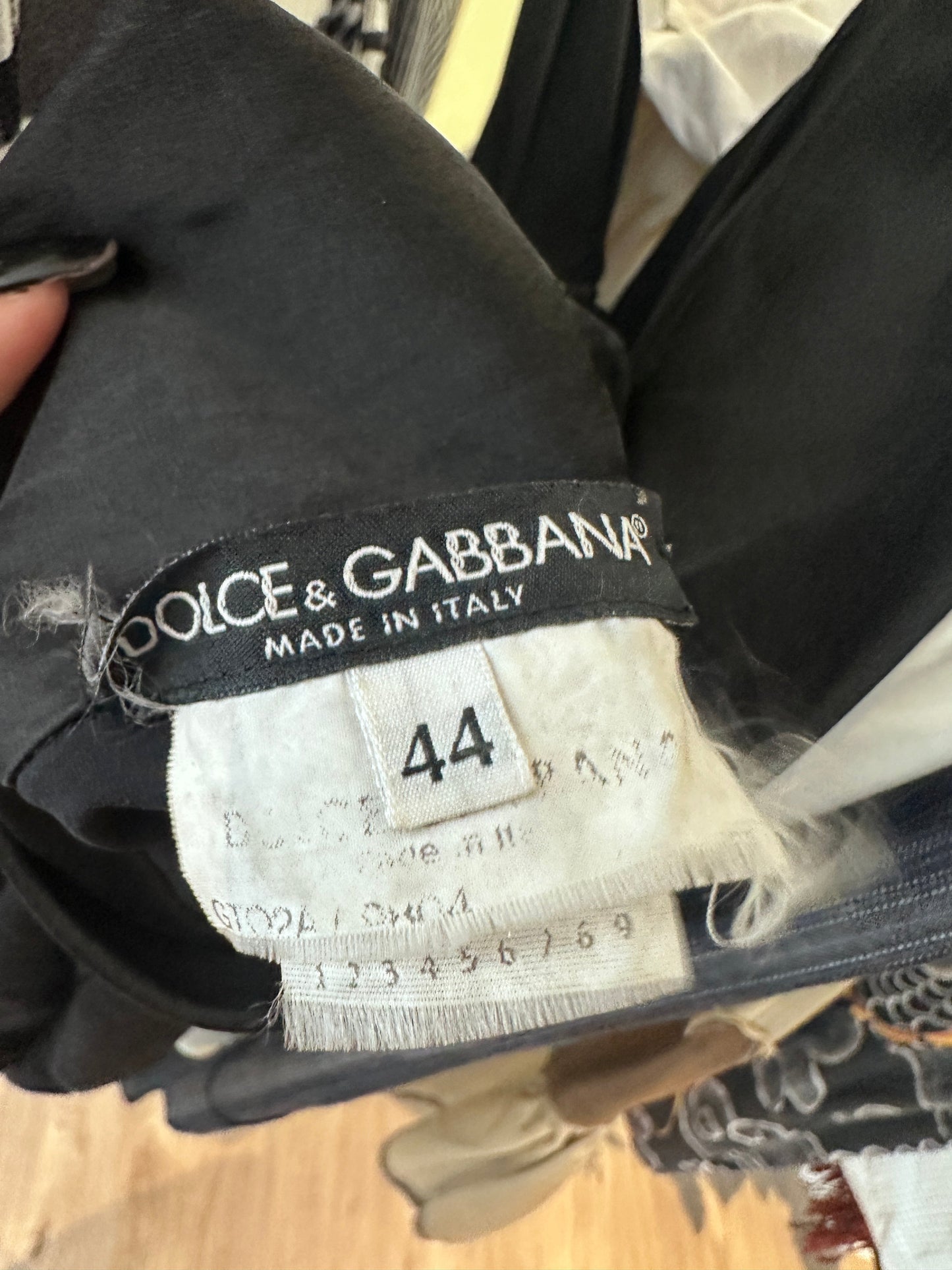 Close-up of a black Dolce & Gabbana garment showing the inner neck label with size 44 and the brand name 'DOLCE & GABBANA MADE IN ITALY'.