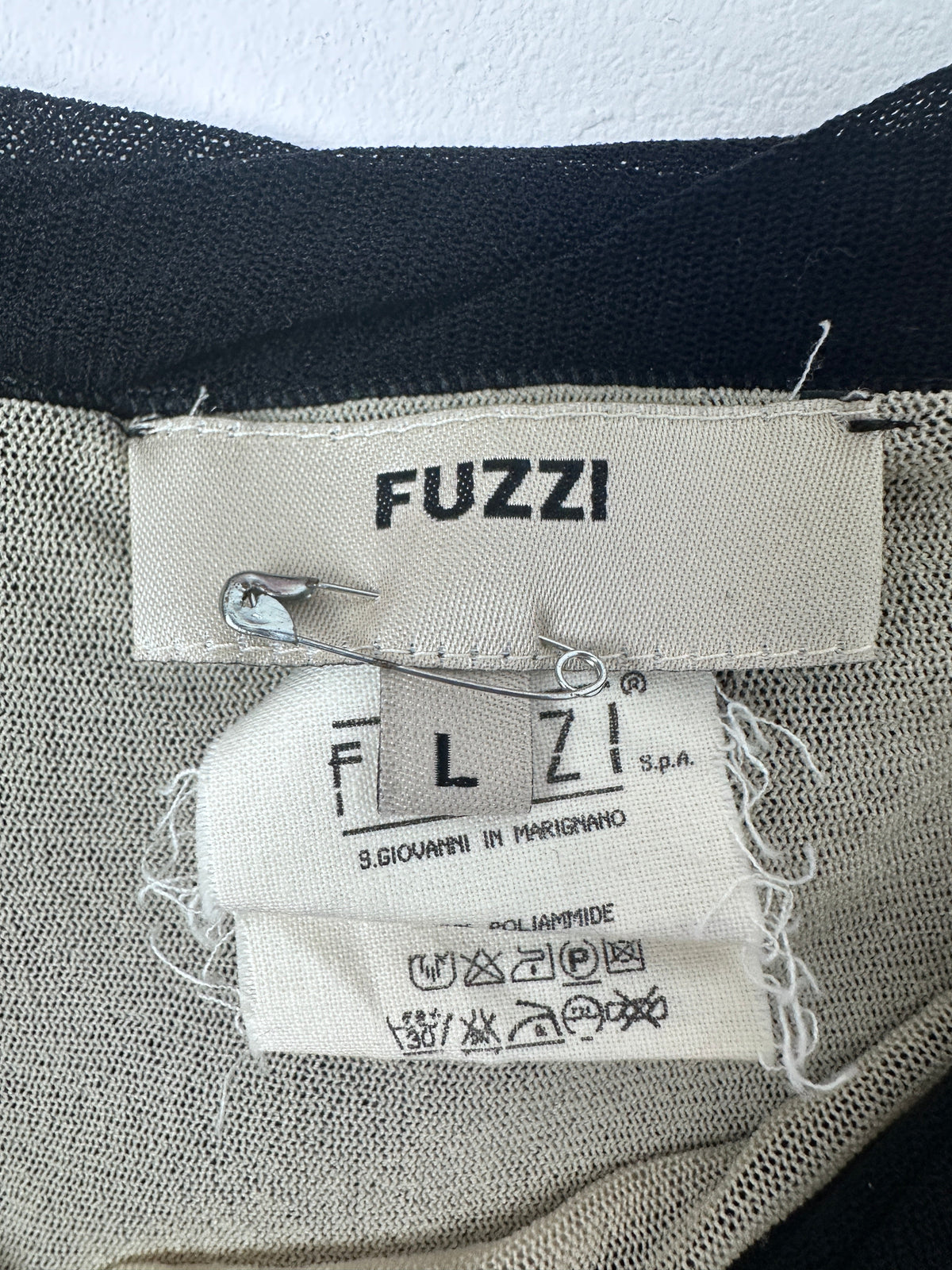 Close-up of a clothing label with 'FUZZI' and 'FL' branding on fabric.