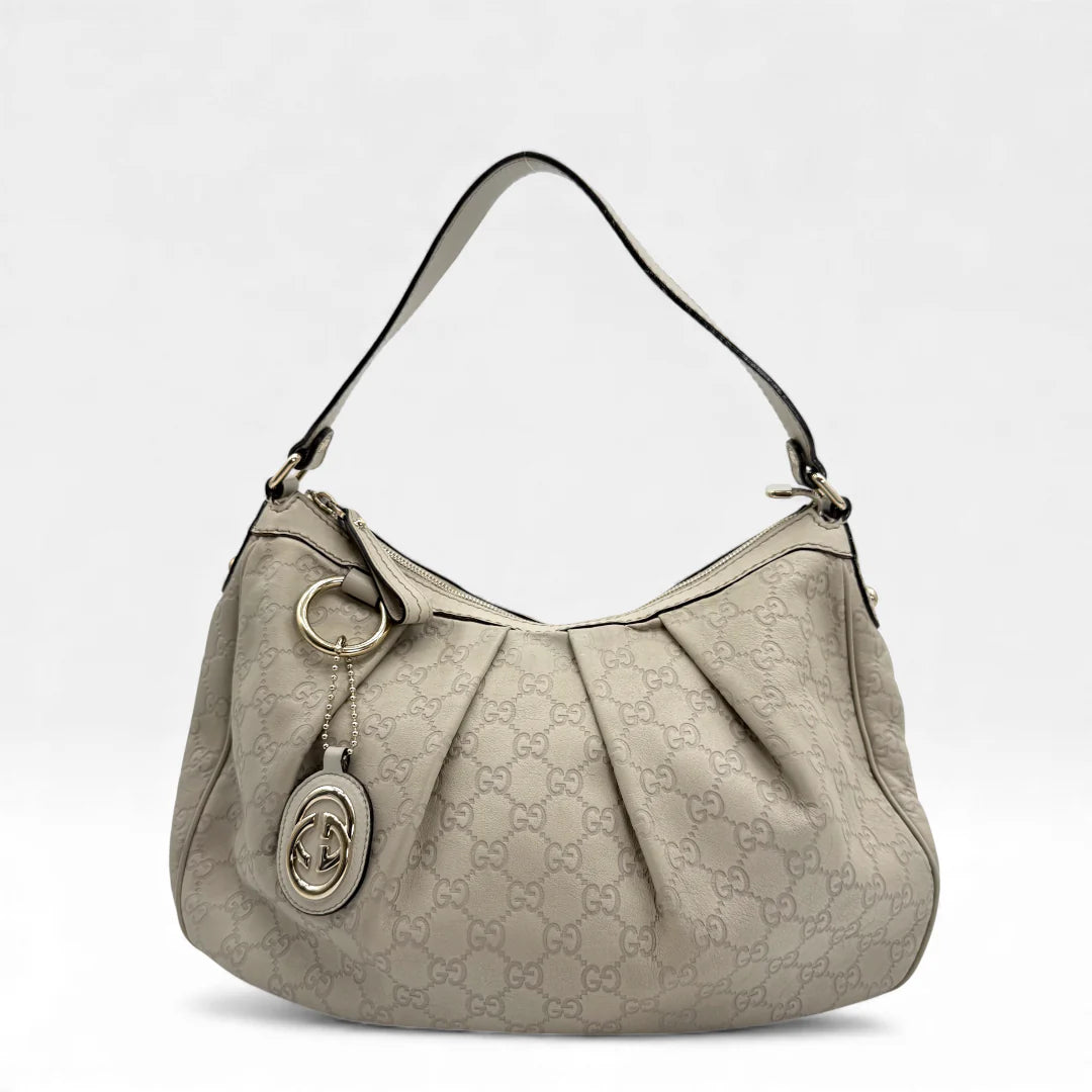 https://cdn.shopify.com/s/files/1/0564/9376/8855/files/Gucci_Handtasche_Sukey_One_aus_Leder_monogram_beige_vintage_GG_handbag_5216.webp?v=1765382538