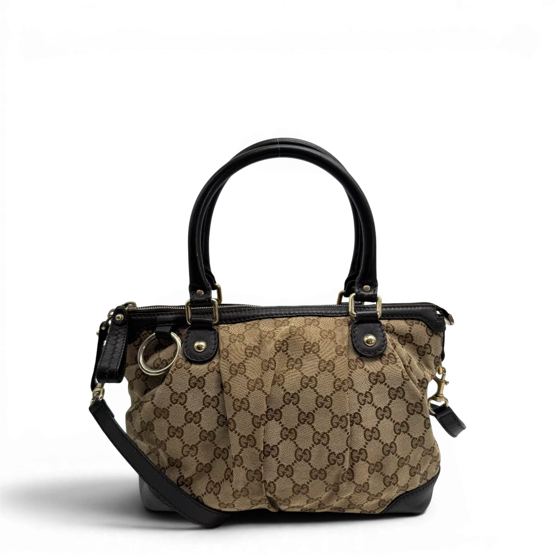 https://cdn.shopify.com/s/files/1/0564/9376/8855/files/Gucci_Handtasche_Sukey_mit_Umhangegurt_monogram_beige_vintage_GG2324.webp?v=1779968392