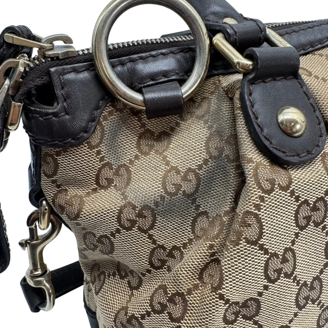 https://cdn.shopify.com/s/files/1/0564/9376/8855/files/Gucci_Handtasche_Sukey_mit_Umhangegurt_monogram_beige_vintage_GG2336.webp?v=1779968393