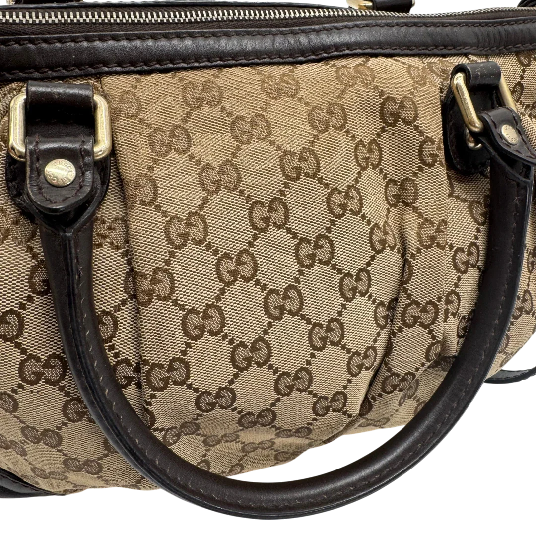 https://cdn.shopify.com/s/files/1/0564/9376/8855/files/Gucci_Handtasche_Sukey_mit_Umhangegurt_monogram_beige_vintage_GG2338.webp?v=1779968393