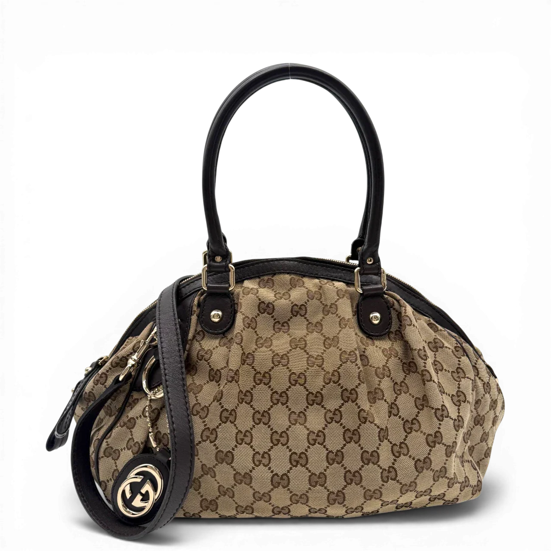 https://cdn.shopify.com/s/files/1/0564/9376/8855/files/Gucci_Handtasche_Sukey_mit_Umhangegurt_monogram_beige_vintage_GG6104.webp?v=1775065489