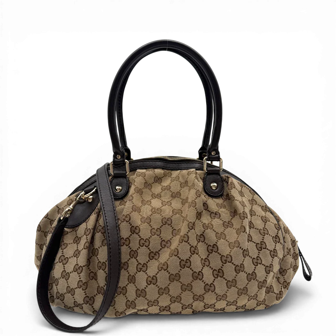 https://cdn.shopify.com/s/files/1/0564/9376/8855/files/Gucci_Handtasche_Sukey_mit_Umhangegurt_monogram_beige_vintage_GG6105.webp?v=1775065519
