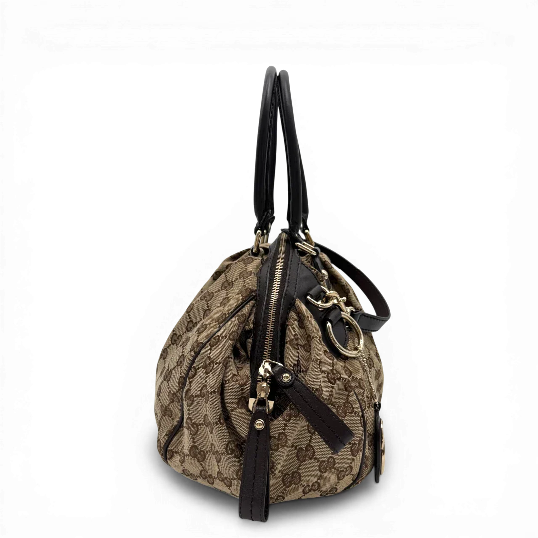 https://cdn.shopify.com/s/files/1/0564/9376/8855/files/Gucci_Handtasche_Sukey_mit_Umhangegurt_monogram_beige_vintage_GG6107.webp?v=1775065519