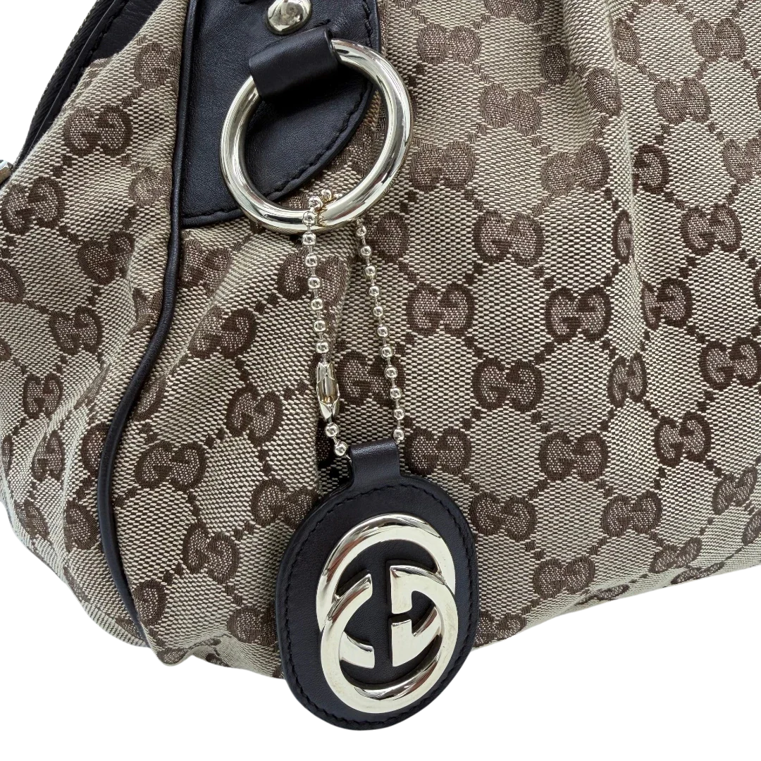 https://cdn.shopify.com/s/files/1/0564/9376/8855/files/Gucci_Handtasche_Sukey_mit_Umhangegurt_monogram_beige_vintage_GG6114.webp?v=1775065519