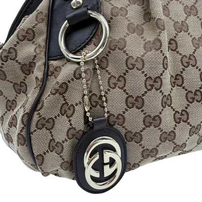 https://cdn.shopify.com/s/files/1/0564/9376/8855/files/Gucci_Handtasche_Sukey_mit_Umhangegurt_monogram_beige_vintage_GG6114.webp?v=1775065519