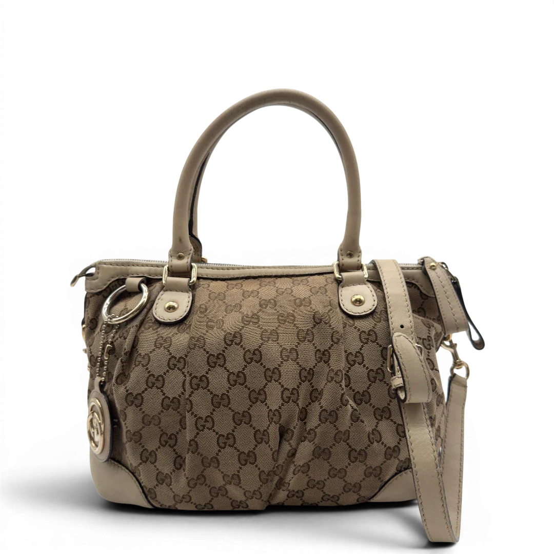 https://cdn.shopify.com/s/files/1/0564/9376/8855/files/Gucci_Handtasche_Sukey_mit_Umhangegurt_monogram_beige_vintage_GG7928.webp?v=1779966403