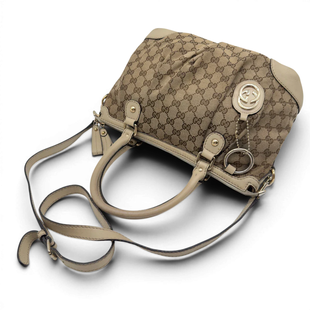 https://cdn.shopify.com/s/files/1/0564/9376/8855/files/Gucci_Handtasche_Sukey_mit_Umhangegurt_monogram_beige_vintage_GG7937.webp?v=1779966403