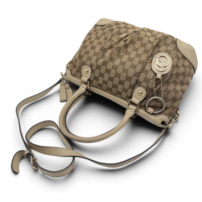 https://cdn.shopify.com/s/files/1/0564/9376/8855/files/Gucci_Handtasche_Sukey_mit_Umhangegurt_monogram_beige_vintage_GG7937.webp?v=1779966403